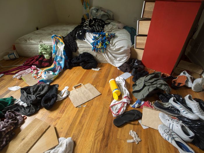 A room filled with discarded clothes and trash scattered across the floor.