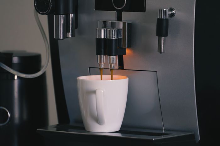Espresso flowing into a white cup from a coffee machine, highlighting a sleek modern kitchen gadget