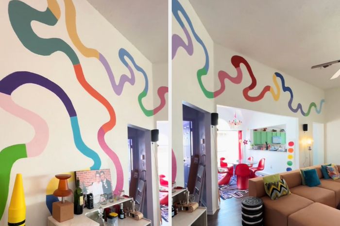 A vibrant mural of wavy, rainbow-colored lines on a wall above a shelf filled with various objects, along with a large crayon sculpture