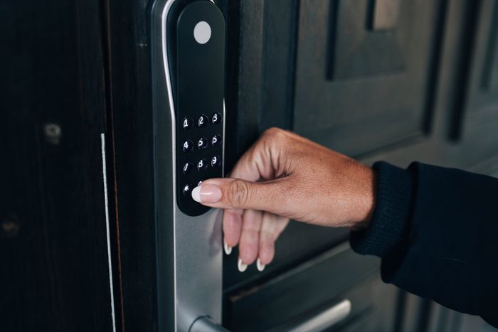 A person entering a code into a digital keypad to access a secure door