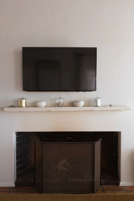 A fireplace with a TV mounted above it, decorative candles on the mantel, and a protective screen in front.