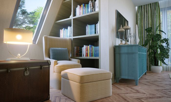A cozy reading nook with a comfortable armchair, ottoman, a built-in bookshelf stacked with books, a lamp, a chest, and a blue dresser, positioned near a window showcasing the lush greenery outside.