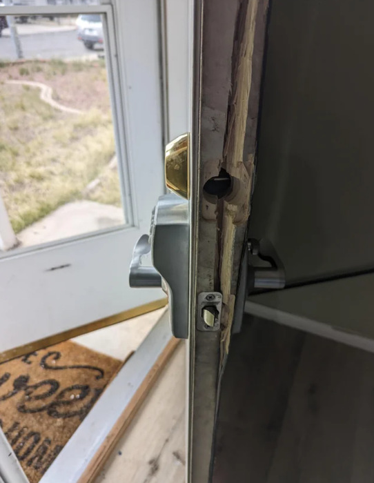 A close-up of a slightly open door latch, showing a glimpse of the outdoors through the gap.