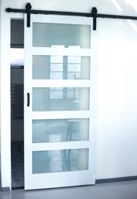 A frosted glass sliding door, slightly ajar, offering a peek into a room with a table.