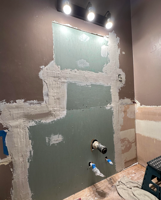 A partially renovated bathroom with exposed plumbing and unfinished walls