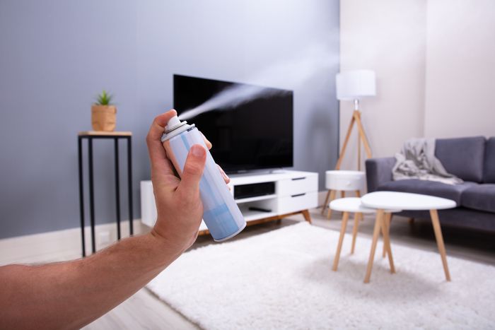 A person spraying air freshener inside a room.