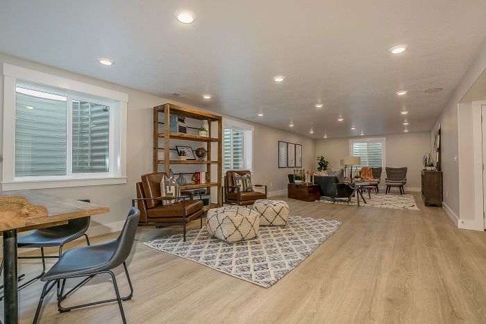 A spacious living area featuring contemporary furniture, a well-stocked bookshelf, plenty of seating, and numerous recessed lights.