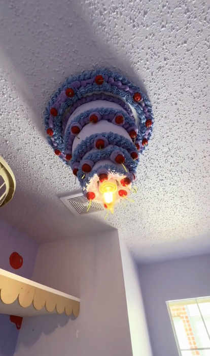 A close-up view of the cake chandelier, with multiple layers decorated in icing and cherries