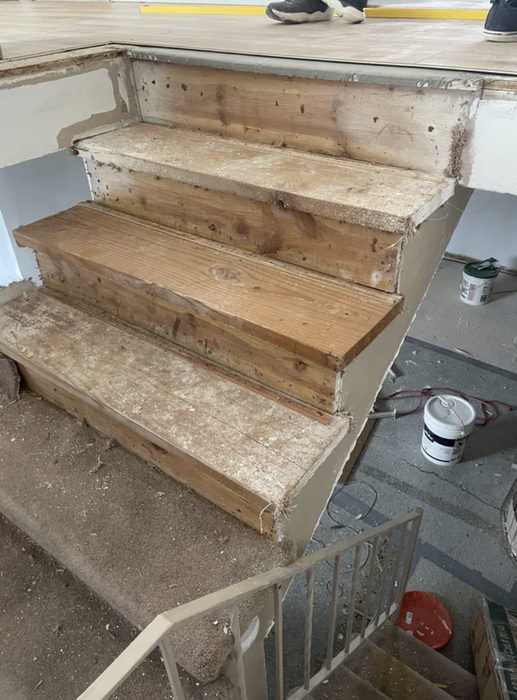 A set of wooden stairs under construction with the treads removed, exposing the risers and stringers