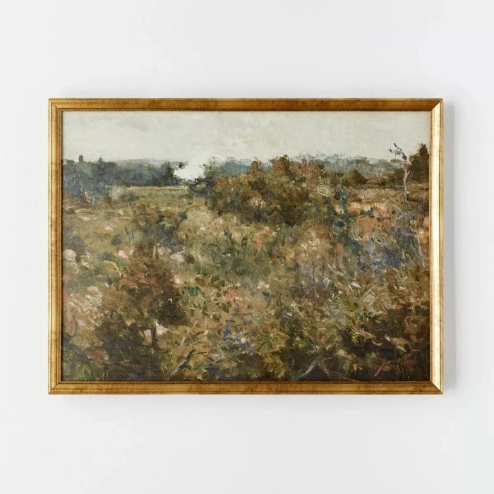 A framed landscape painting of a peaceful countryside scene with sprawling fields and distant trees, set against a simple backdrop