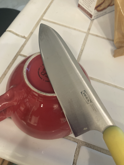 Knife resting on a red teapot on a tiled counter