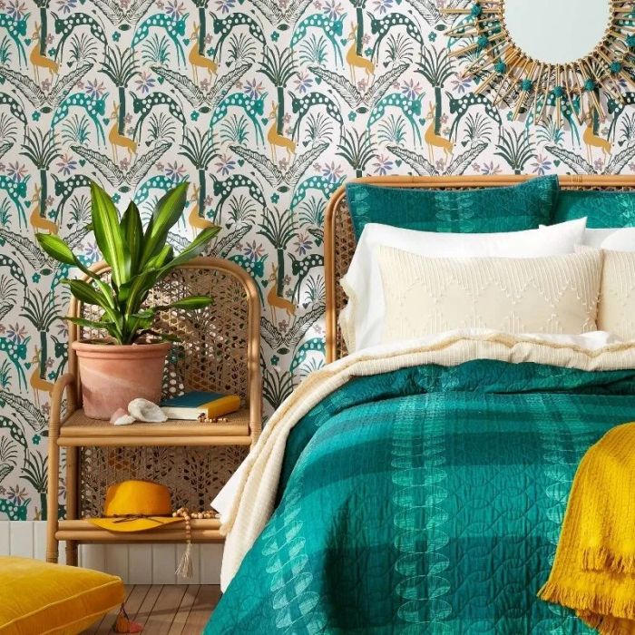 A chic bedroom setting featuring patterned wallpaper, a rattan headboard, and a mix of cozy textiles on the bed