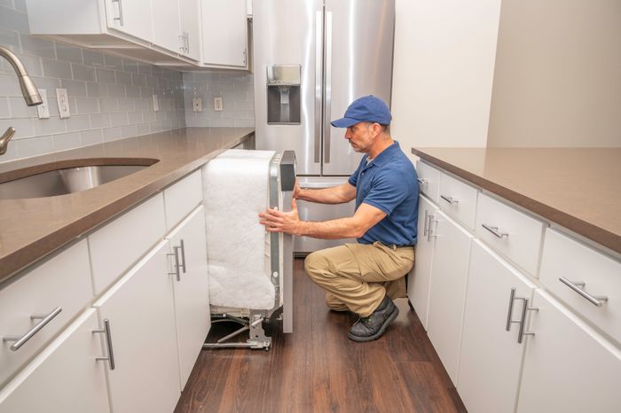 Technician installing a dishwasher in a kitchen.
