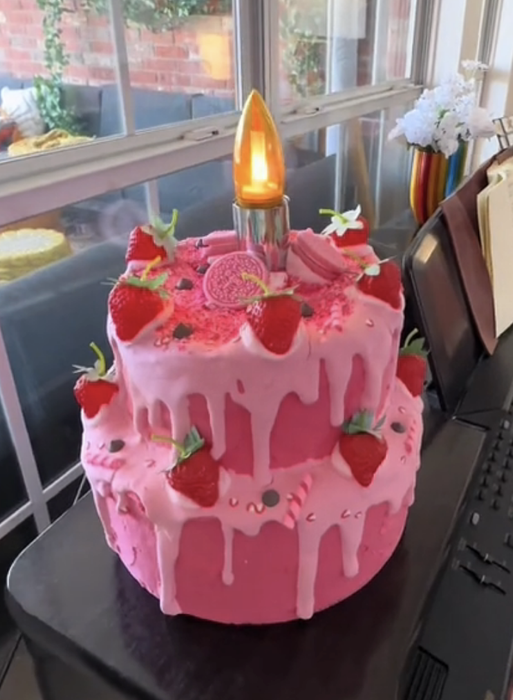 A charming strawberry cake lamp with a single candle flickering on top