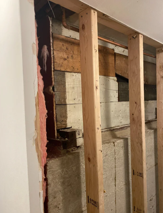 An incomplete interior wall revealing exposed wooden studs and insulation.