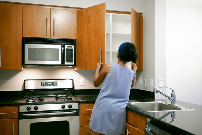 A woman inspecting the kitchen cabinets.
