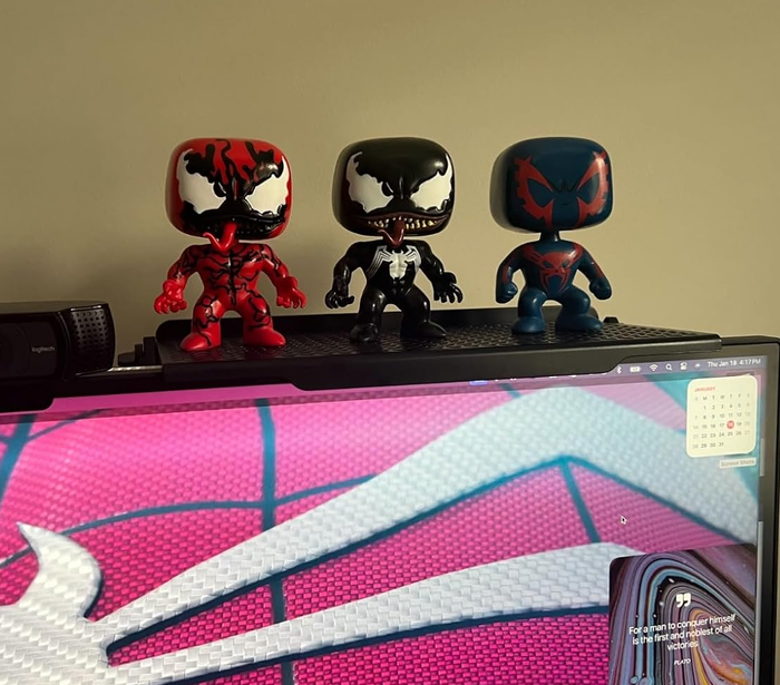 Three Funko Pop figures, featuring Spider-Man variants, displayed on top of a monitor.