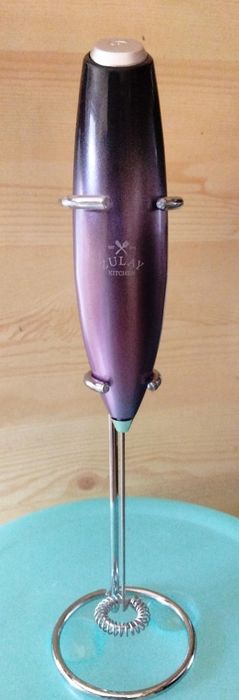 Electric handheld milk frother from Lulu Kitchen resting on a light blue surface.