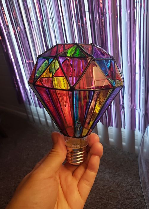 A reviewer holding up the stained glass lightbulb