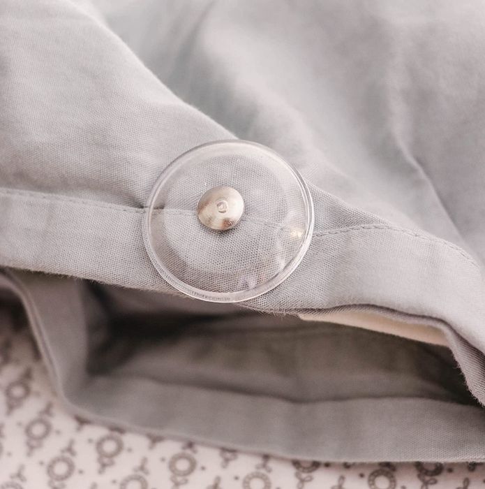 A clear circular pin attached to a duvet cover, keeping the duvet secure in place.