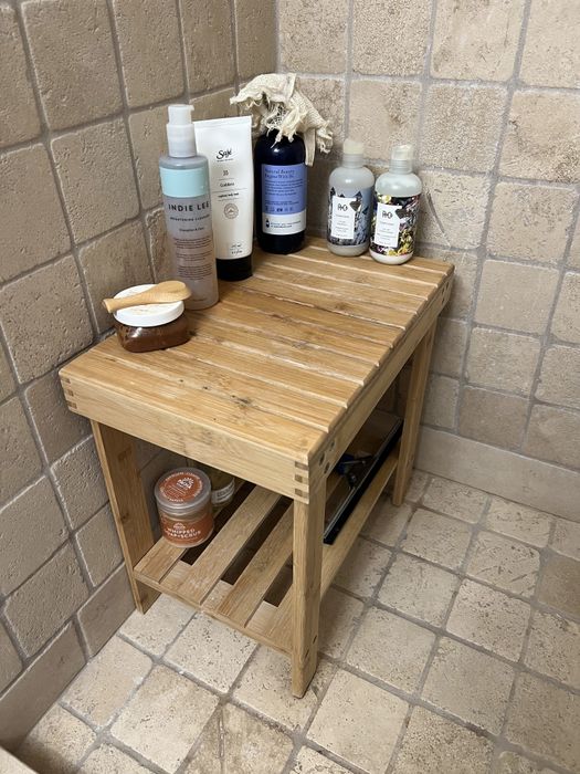 A bamboo shower stool is placed inside a shower area