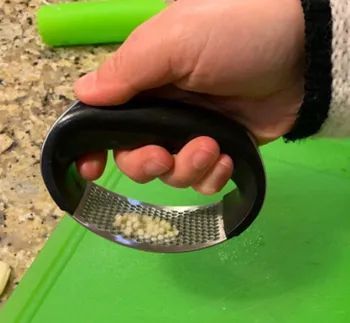 Close-up of a hand holding the garlic rocker tool