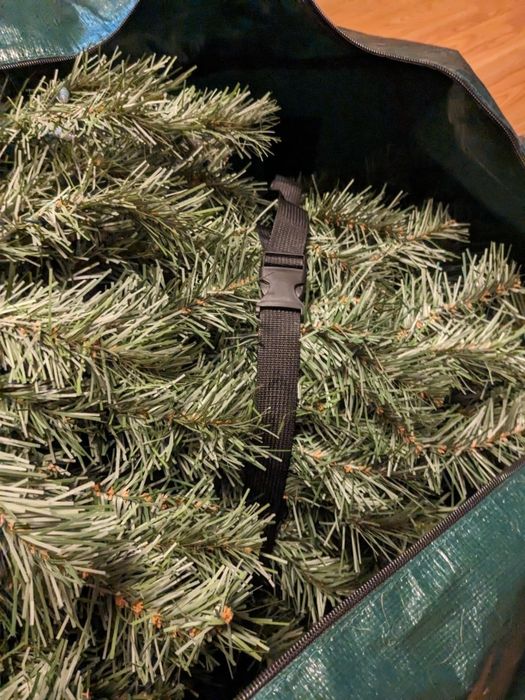 Artificial Christmas tree branches neatly packed in a large, sturdy green storage bag
