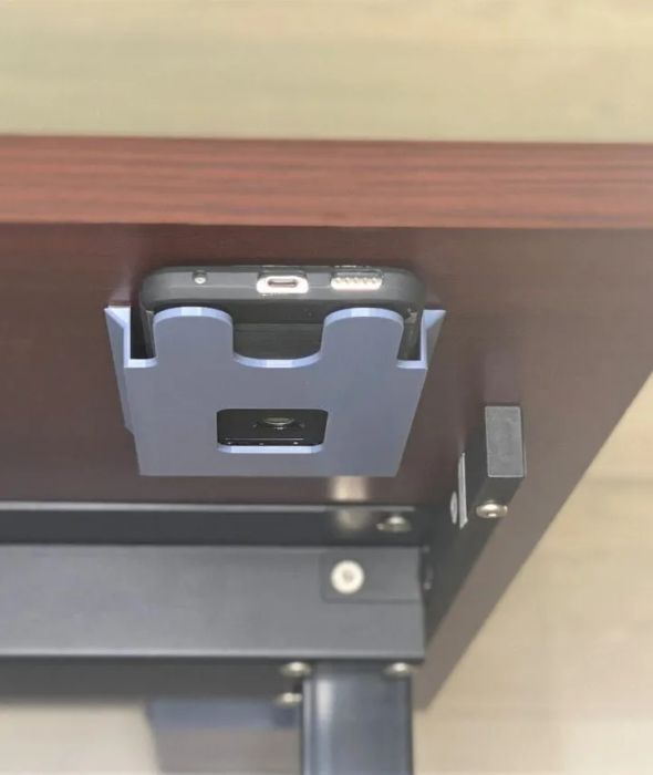 The phone holder mounted under a desk.