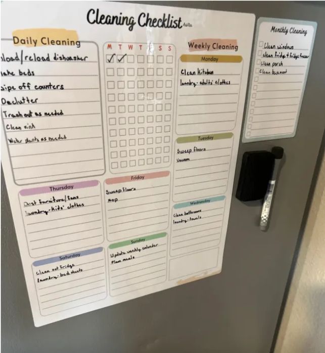 A cleaning checklist on a fridge with designated daily, weekly, and monthly tasks. Includes a dry-erase pen attached for easy note-taking.