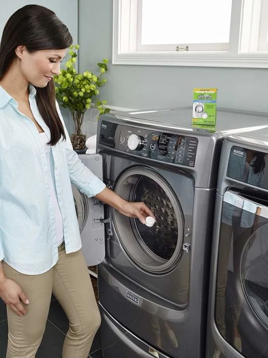 A reviewer placing a tablet into the washing machine.