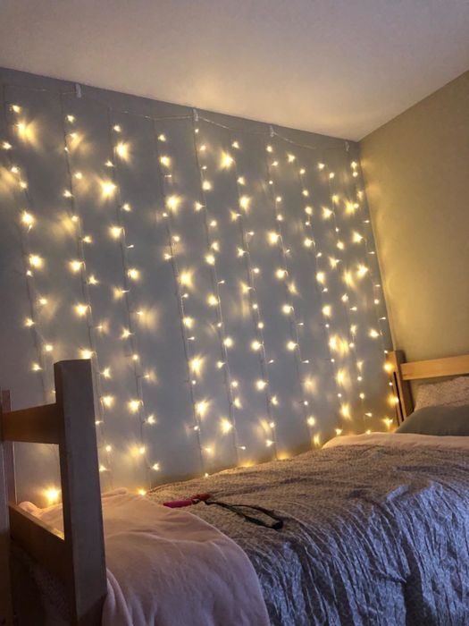The string lights cascading down a wall near a bed, glowing softly in the dark.