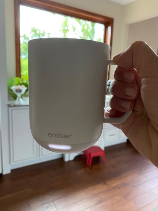 A reviewer proudly holding up the white Ember mug