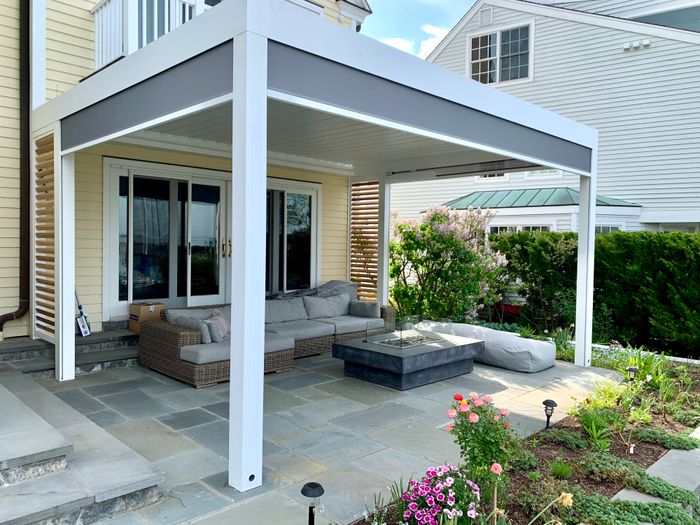 Home exterior featuring patio seating under a pergola, next to a garden