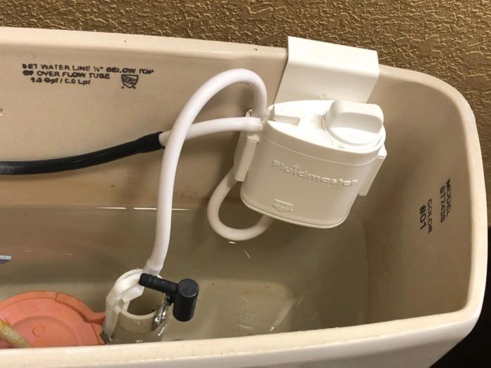 A customer photo showing the installed system, which attaches to the tank and connects to two of the toilet's internal tubes