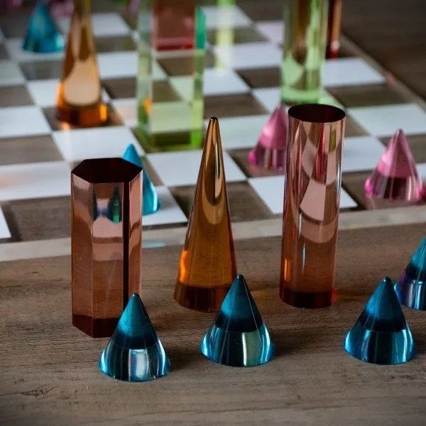 A sophisticated glass chess set featuring reflective pieces arranged on a polished wooden board, blending elegance with strategic play.