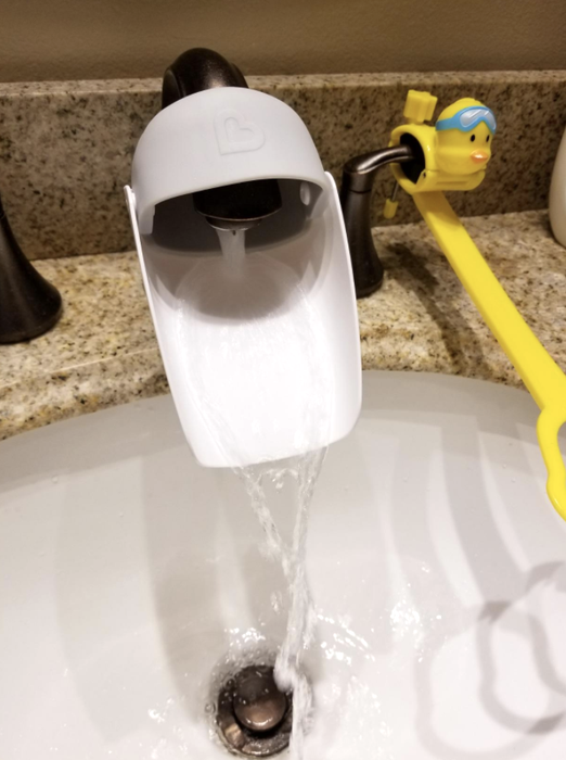 A close-up of a faucet extender attached to a faucet, making it easier for little ones to reach