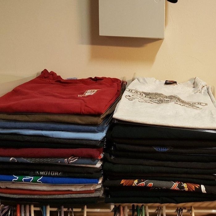 Perfectly folded and stacked T-shirts sitting neatly on a shelf after using the closet organizer and shirt folder.
