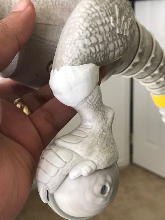 A toy plastic dinosaur whose knee joint was fixed with white Sugru.
