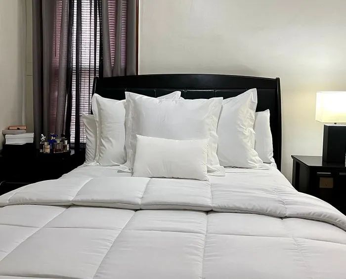 A beautifully arranged bed with fluffy pillows and a plush, quilted comforter