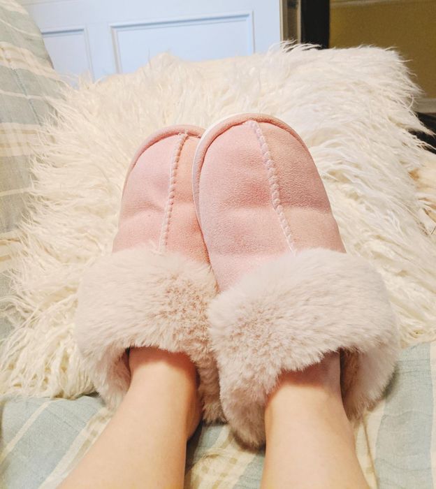 Cozy, plush slippers resting on feet, nestled in a plaid blanket, embodying the essence of home comfort shopping