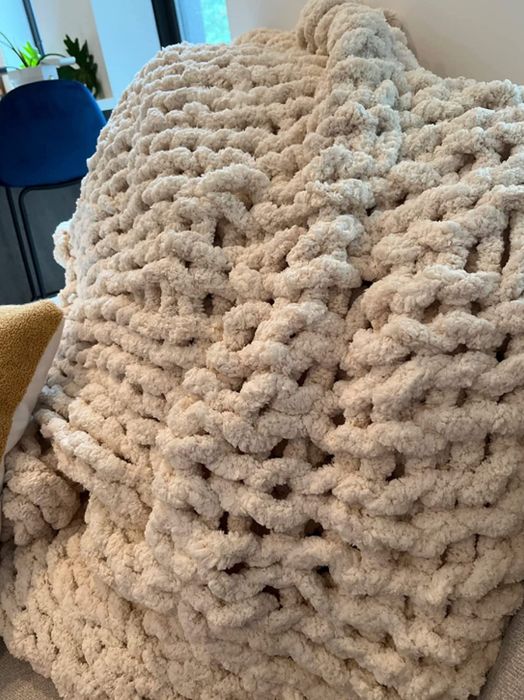A reviewer showcasing the cozy hand-knit blanket up close, highlighting its texture