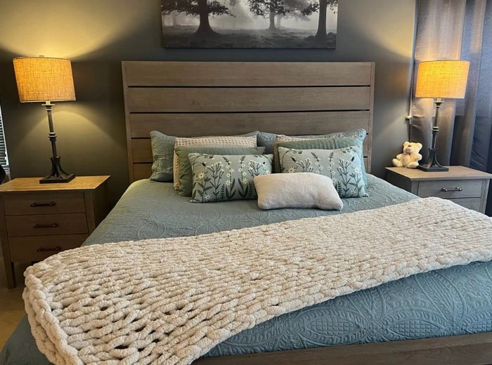 A reviewer displaying the hand-knit throw on their bed