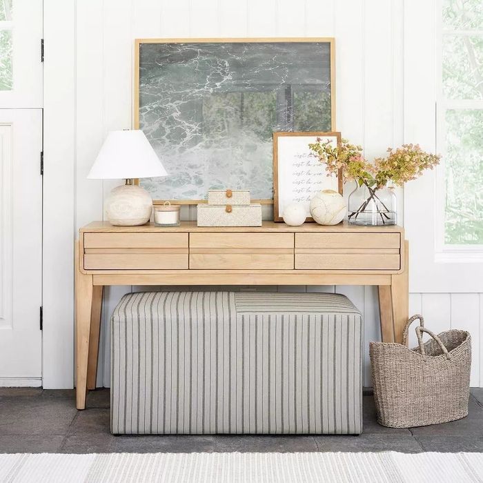 Wooden vanity with a coordinating striped ottoman, large mirror, decorative accents, and a basket, styled for a home decor shopping feature