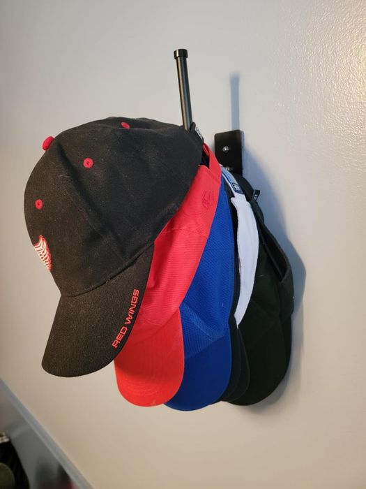 A variety of baseball caps hanging on a wall-mounted rack, perfect for displaying or organizing your collection.