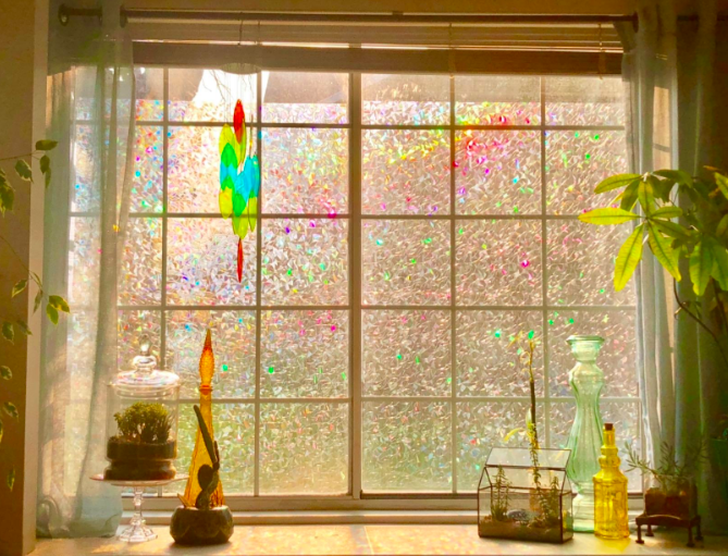 A reviewer's image showing the privacy window film with vibrant beams of light shining through a large window