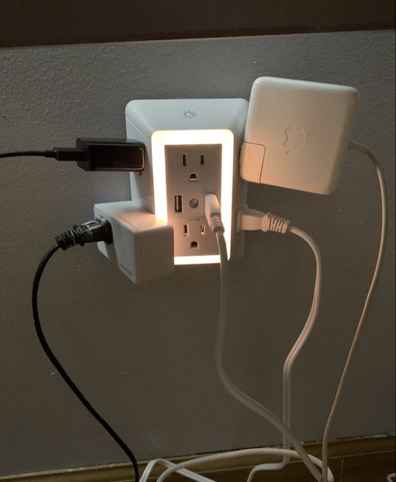 A charger with several large plugs plugged into it, each occupying one of the outlets.
