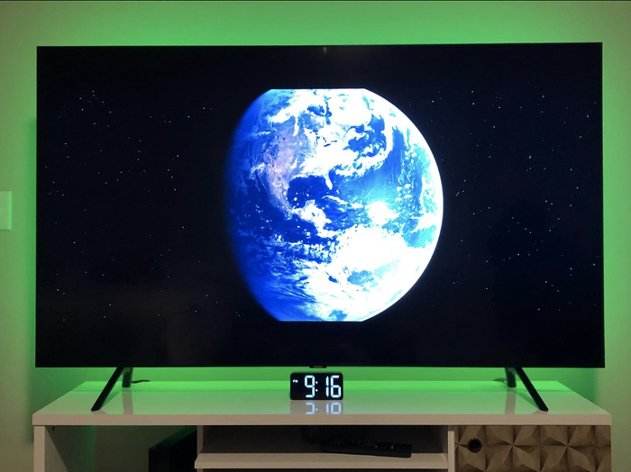 A reviewer’s TV illuminated with a soft green glow from the LED light strip for a calming atmosphere.