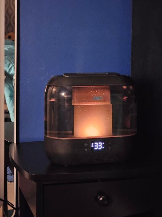 A sleek humidifier resting on a nightstand, displaying 33% humidity, casting a soft and soothing glow.