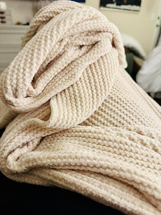 A plush, cream-colored chenille blanket, perfect for cozying up in style.