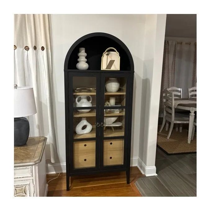 A sleek black arched cabinet adorned with decorative vases and storage boxes, seamlessly complementing a modern living room beside a chic dining area.